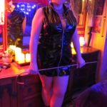 Standing in short black pvc dress holding cane